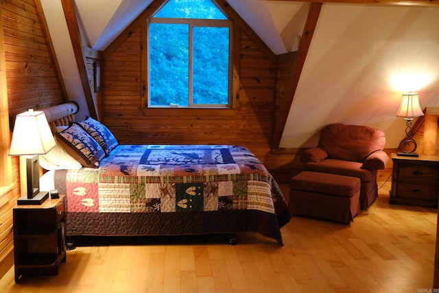 bedroom featuring light hardwood / wood-style floors, lofted ceiling, and wood walls