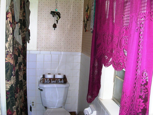 bathroom with toilet and tile walls