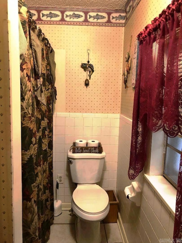 bathroom with tile patterned floors, tile walls, and toilet