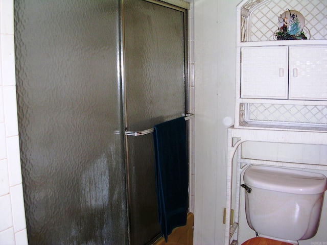 bathroom featuring toilet and a shower with door