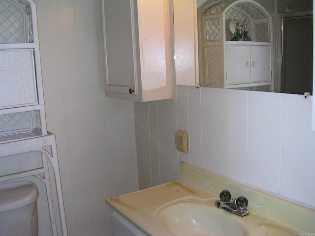 bathroom featuring vanity, toilet, and backsplash