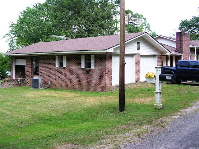 view of side of property with a lawn, central AC unit, and a garage