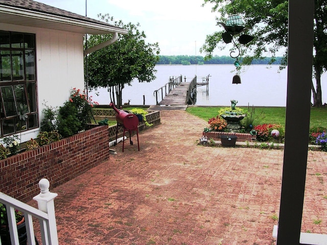 view of patio with a water view and a dock