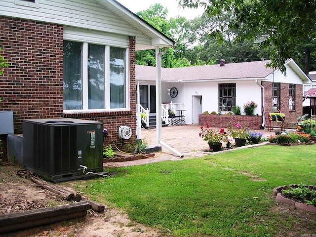 rear view of house with cooling unit, a patio area, and a yard