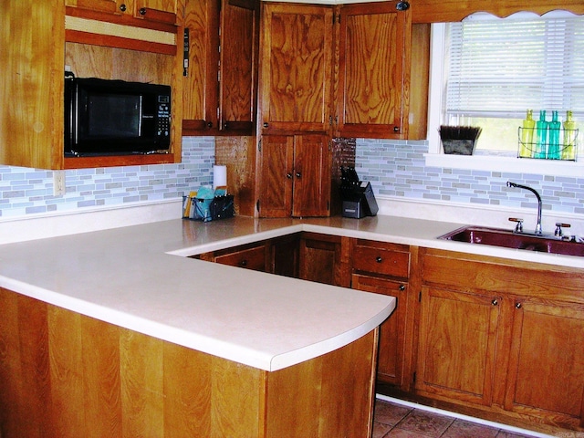 kitchen with tile patterned floors, kitchen peninsula, decorative backsplash, and sink