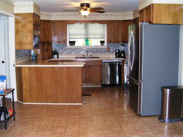 kitchen with kitchen peninsula, tasteful backsplash, stainless steel appliances, ceiling fan, and sink