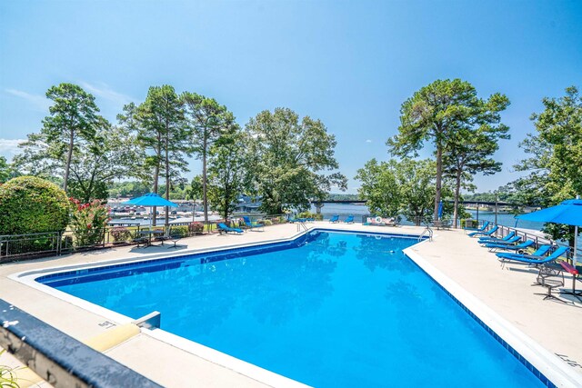 view of swimming pool with a patio and a water view