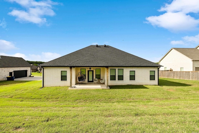 rear view of house featuring fence, a garage, a patio, ceiling fan, and a lawn