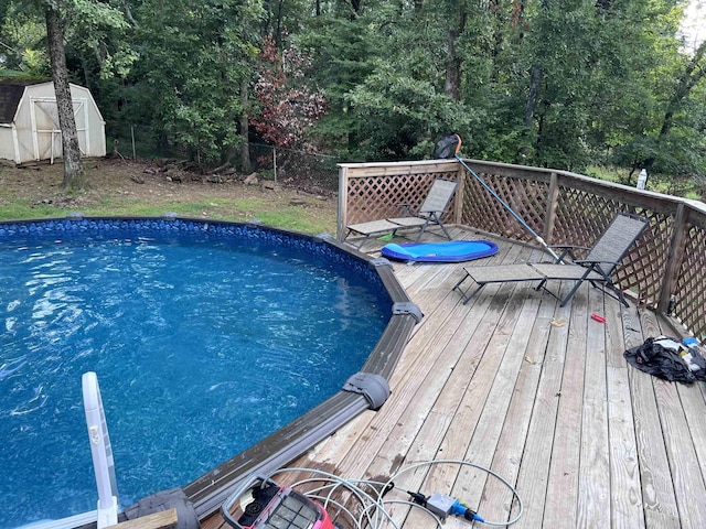 view of swimming pool with a wooden deck and a storage unit