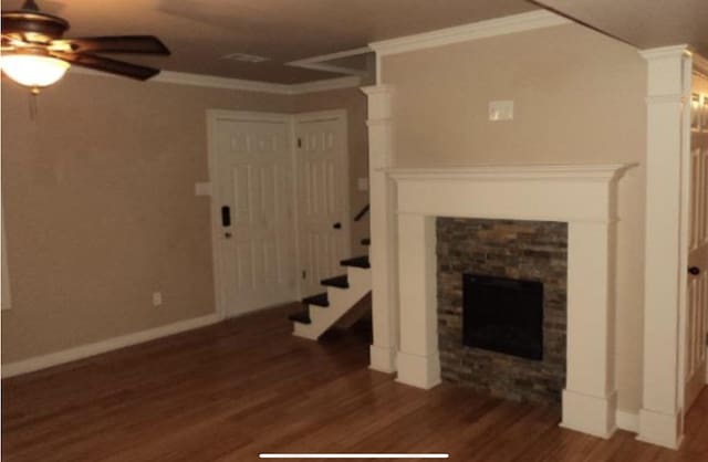 unfurnished living room featuring a stone fireplace, dark wood-type flooring, and ornamental molding