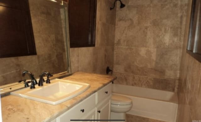 full bathroom featuring vanity, tiled shower / bath, and toilet