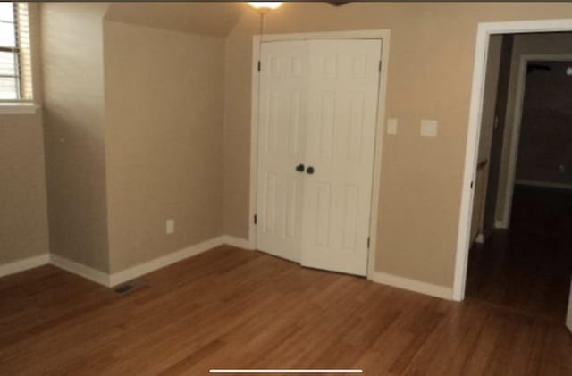 unfurnished bedroom with dark hardwood / wood-style floors and a closet