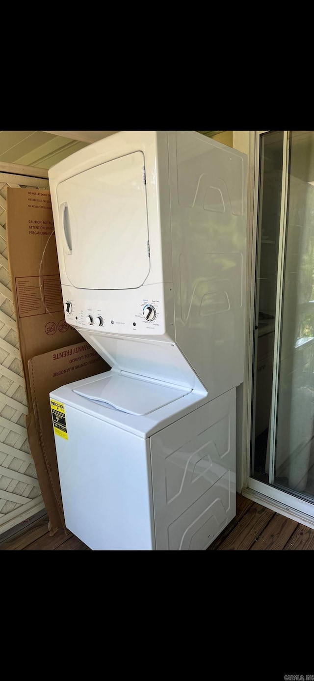 laundry room with stacked washer / dryer and hardwood / wood-style flooring