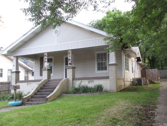 view of front of home with covered porch, central AC, and a front yard