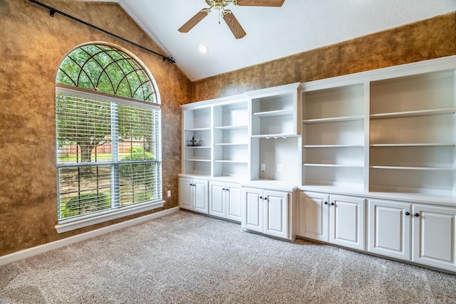 unfurnished living room featuring light carpet, vaulted ceiling, a wealth of natural light, and ceiling fan