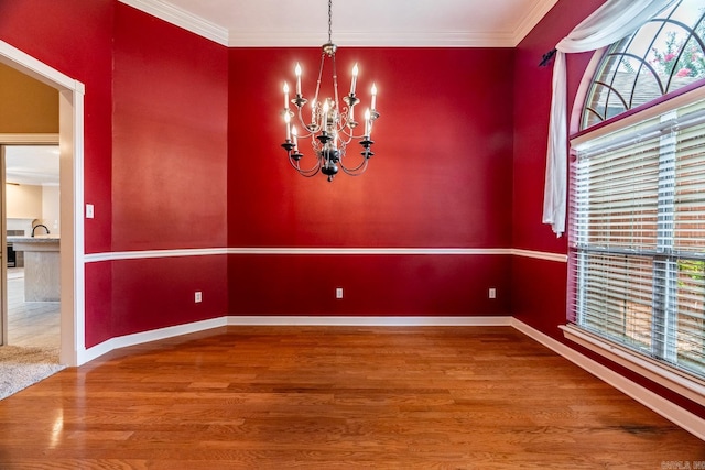 unfurnished dining area featuring hardwood / wood-style flooring, ornamental molding, and an inviting chandelier