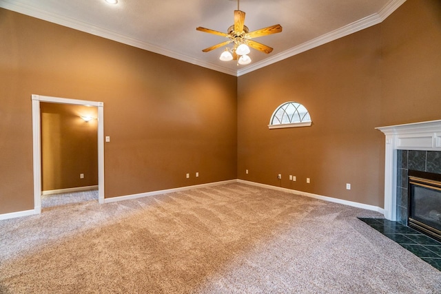 unfurnished living room featuring carpet flooring, ceiling fan, ornamental molding, and a tiled fireplace