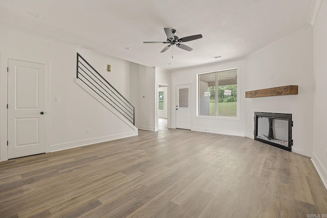 unfurnished living room featuring hardwood / wood-style flooring, crown molding, and ceiling fan