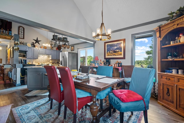 dining area with dark hardwood / wood-style flooring, a notable chandelier, and high vaulted ceiling