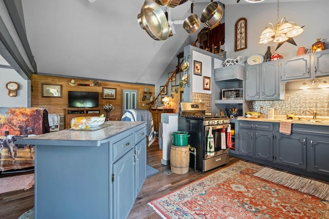 kitchen featuring backsplash, stainless steel appliances, a notable chandelier, wood-type flooring, and wood walls