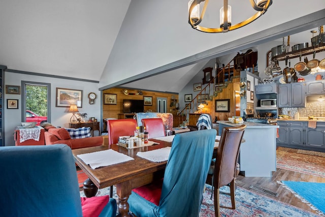 dining space with high vaulted ceiling, hardwood / wood-style floors, and a chandelier