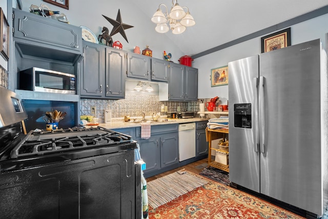 kitchen featuring lofted ceiling, sink, pendant lighting, stainless steel appliances, and tasteful backsplash