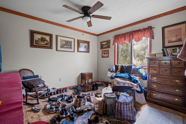 bedroom featuring hardwood / wood-style flooring, ornamental molding, a textured ceiling, and ceiling fan