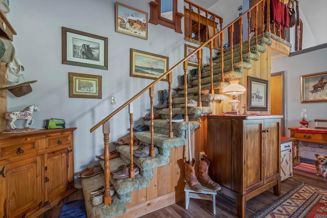 stairs with wood-type flooring and a high ceiling