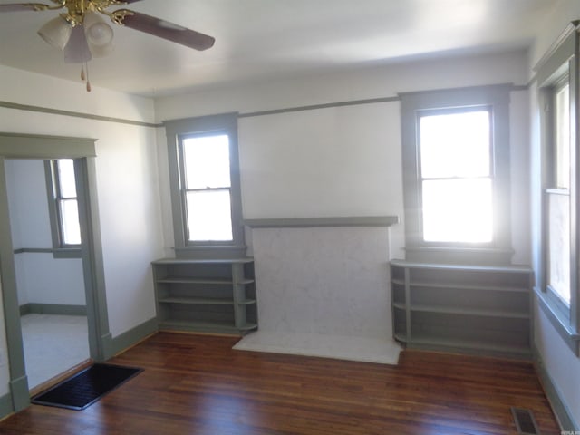 unfurnished living room featuring dark hardwood / wood-style floors, a wealth of natural light, and ceiling fan