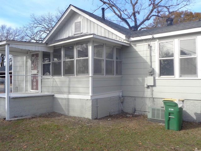 view of side of property featuring a sunroom, central AC unit, and a lawn