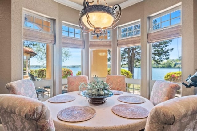 dining space with a water view, ornamental molding, and a chandelier