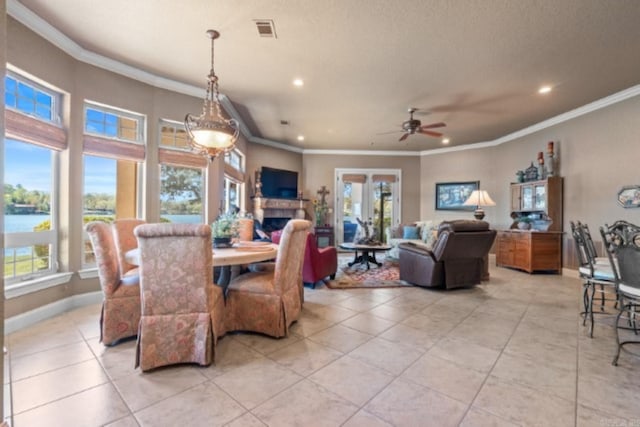 tiled dining room with ceiling fan, a water view, and ornamental molding