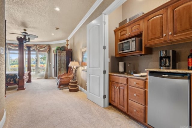 kitchen with light carpet, sink, ceiling fan, a textured ceiling, and stainless steel appliances