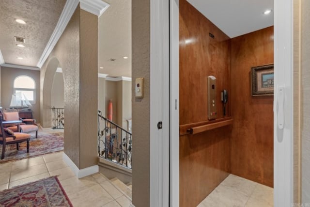 hall with light tile patterned floors, a textured ceiling, elevator, and crown molding