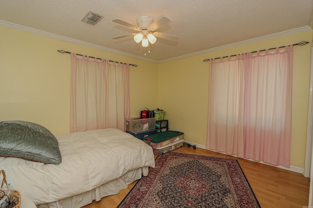 bedroom with wood-type flooring, a textured ceiling, ceiling fan, and crown molding