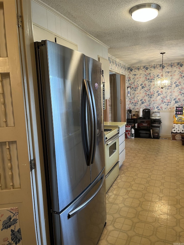 kitchen featuring stainless steel fridge, a textured ceiling, pendant lighting, a chandelier, and range