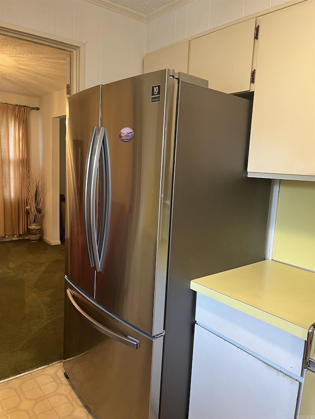 kitchen with a textured ceiling, white cabinetry, and stainless steel refrigerator