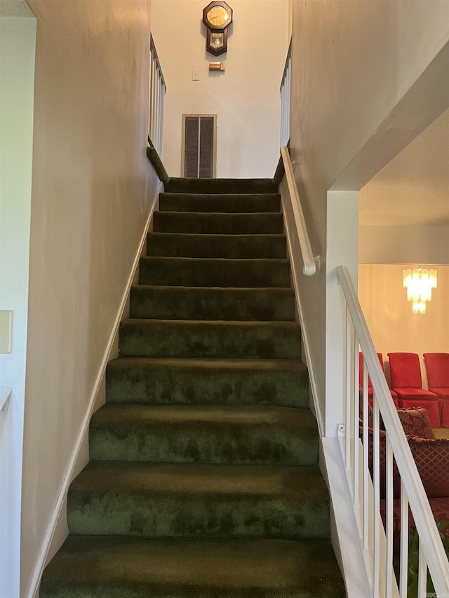 stairway featuring a notable chandelier