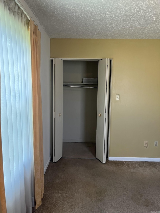 unfurnished bedroom featuring carpet flooring, a textured ceiling, and a closet