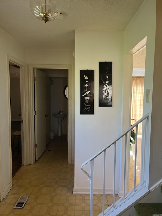 corridor with sink and a textured ceiling