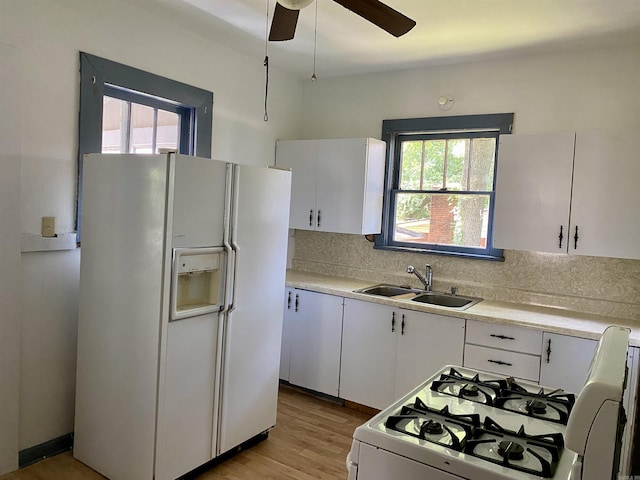 kitchen with light wood-type flooring, backsplash, white appliances, sink, and white cabinets