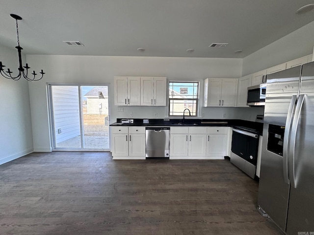 kitchen with pendant lighting, dark hardwood / wood-style floors, stainless steel appliances, and white cabinets