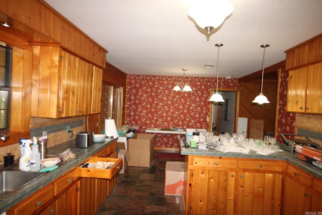 152 Hempstead 336, Mccaskill, AR 71847 - kitchen with wallpapered walls, a peninsula, brown cabinetry, stone finish flooring, and hanging light fixtures