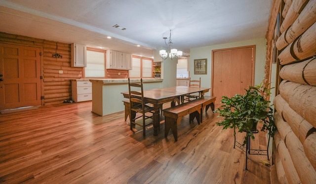 dining space with a notable chandelier, rustic walls, and light hardwood / wood-style flooring