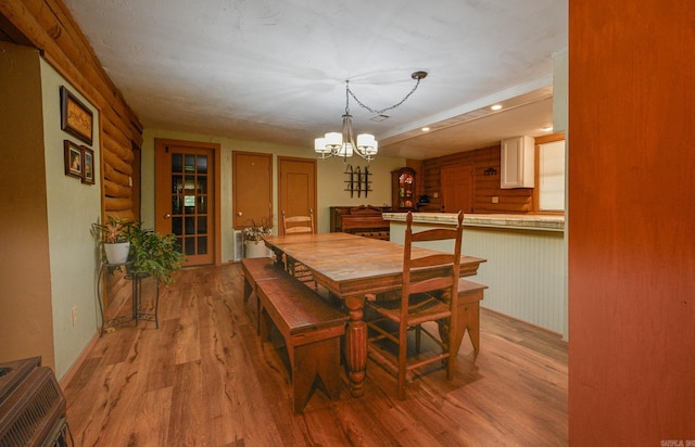 dining room featuring light hardwood / wood-style flooring, rustic walls, and a chandelier