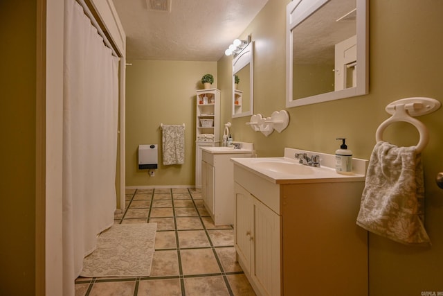 bathroom featuring vanity, tile patterned floors, and a textured ceiling