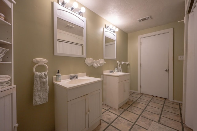 bathroom with vanity, tile patterned flooring, and a textured ceiling