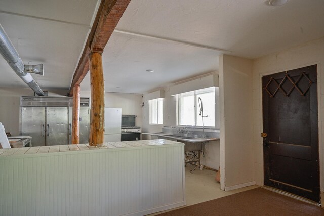 kitchen with stainless steel stove, a kitchen breakfast bar, white refrigerator, tile countertops, and kitchen peninsula