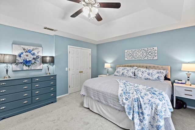 carpeted bedroom featuring a raised ceiling and ceiling fan