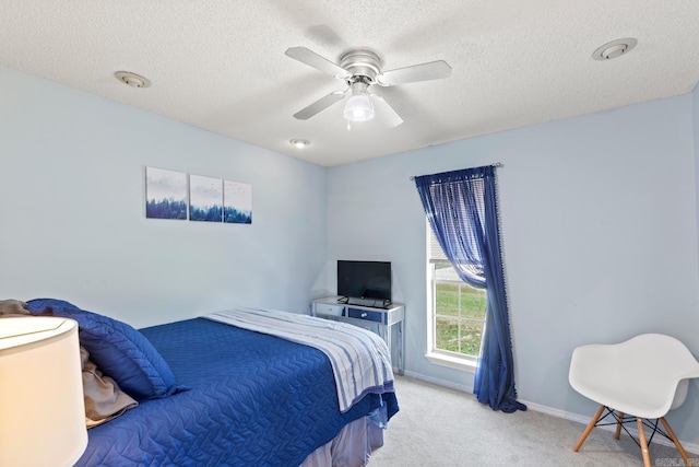 bedroom with ceiling fan, light colored carpet, and a textured ceiling